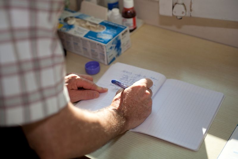 Infirmier renseignant le cahier de liaison au domicile d’un patient