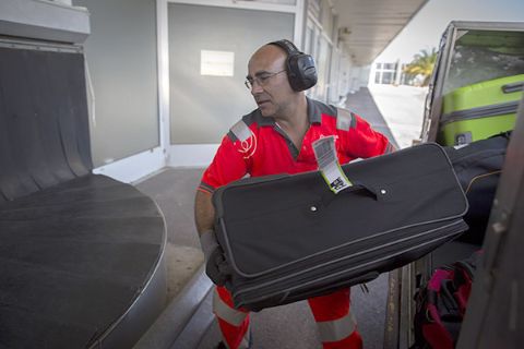 Bagagiste équipé d’un casque de protection contre le bruit travaillant dans une zone aéroportuaire