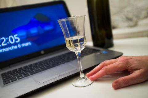 Verre d’alcool posé sur une table devant un ordinateur portable