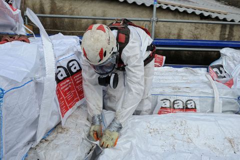 Fermeture d’un big bag de déchets amiantés sur un chantier de remplacement d’une toiture en amiante ciment