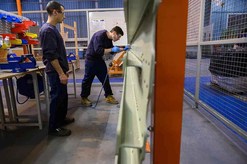 Un nouvel embauché s'entraine sur des bâtis d'assemblage avant de rejoindre la production