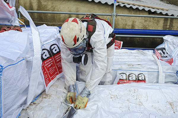 Fermeture d’un « big bag » de déchets d’amiante sur un chantier de remplacement de toiture amiantée