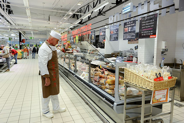 Boucher-charcutier vérifiant sa vitrine dans un supermarché
