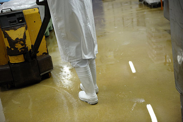 Travailleur portant des bottes antidérapantes se déplaçant sur un sol humide dans une entreprise agroalimentaire